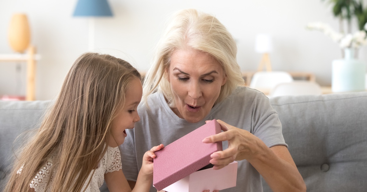 The Art of Giving: Why Small Unique Gifts Mean So Much A young girl and an older woman open their mouths in surprise as they open a small, pink gift box together.